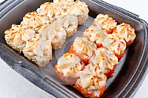 Sushi in plastic packaging. Baked sushi with flying fish roe. Sushi in a plastic box close up.