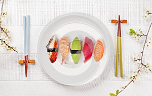 Sushi plate adorned with cherry blossom branch and chopsticks, epitomizing Japanese food culture