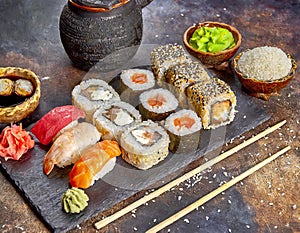 Sushi platter of rolls, maki, nigiri, on dark stone board with sticks