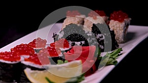 sushi with red black caviar served on a plate swirls in front of the camera close-up a lot of money wealth Luxury