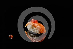 Sushi and red caviar on black acryle with reflection photo