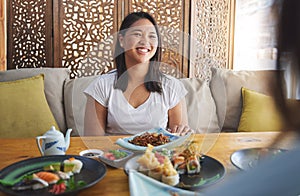 Sushi, restaurant and Japanese food with a woman smile with noodles and fish dish. Lunch, hungry Asian female person and