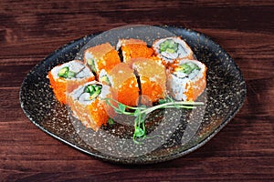 Sushi or rice rolls with red caviar and cucumber on wooden table