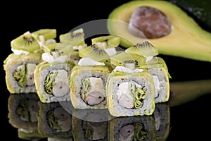 Sushi Roll with crab meat, kiwi and avocado over black backgrou