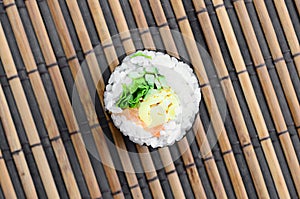 Sushi roll lie on a bamboo straw serwing mat. Traditional Asian food. Top view. Flat lay minimalism shot with copy space