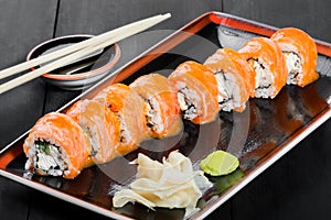 Sushi Roll - Maki Sushi made of salmon, cucumber, avocado and cream cheese on dark wooden background.