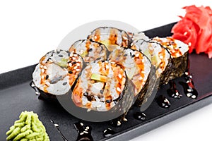 Sushi Roll - Maki Sushi made of smoked eel, Crab meat, avocado on black plate isolated over white background.