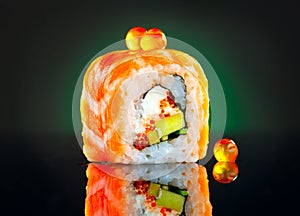 Sushi roll over black background. California sushi roll with salmon, vegetables, flying fish roe