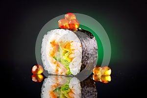 Sushi roll over black background. Sushi roll with tuna, vegetables, flying fish roe and caviar closeup