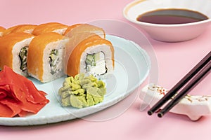 Sushi roll Philadelphia with salmon and cream cheese on a plate with ginger and wasabi. Sushi menu. Japanese food concept.