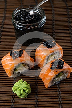 Sushi roll Philadelphia with salmon, smoked eel, avocado, cream cheese on black background. Japanese food.