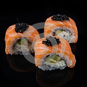Sushi roll Philadelphia with salmon, smoked eel, avocado, cream cheese on black background. Japanese food.