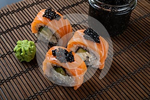 Sushi roll Philadelphia with salmon, smoked eel, avocado, cream cheese on black background. Japanese food.