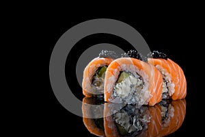 Sushi roll Philadelphia with salmon, smoked eel, avocado, cream cheese on black background. Japanese food.