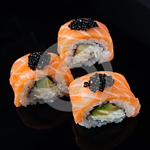 Sushi roll Philadelphia with salmon, smoked eel, avocado, cream cheese on black background. Japanese food.