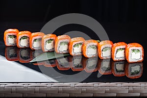 Sushi roll (Philadelphia) with salmon smoked eel avocado cream cheese on black background. Sushi menu. Japanese food