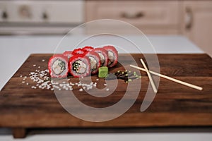 Sushi roll with salmon, avocado, cucumber and red caviar.