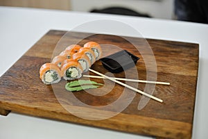 Sushi roll with salmon, avocado, cucumber and wasabi on wooden board