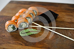 Sushi roll with salmon, avocado, cucumber and wasabi on wooden board