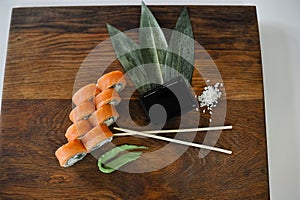 Sushi roll with salmon, avocado, cucumber and wasabi on wooden board