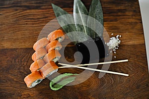 Sushi roll with salmon, avocado, cucumber and wasabi on wooden board