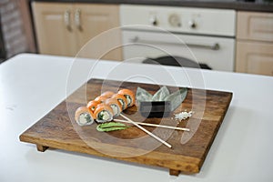 Sushi roll with salmon, avocado, cucumber and wasabi on wooden board