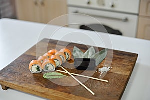 Sushi roll with salmon, avocado, cucumber and wasabi on wooden board