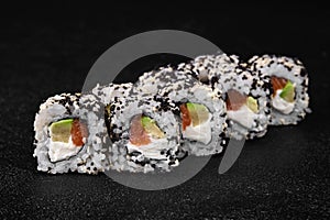 Sushi roll with salmon and avocado inside and black flying fish roe on top