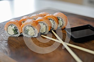 Sushi roll with salmon, cucumber on wooden board