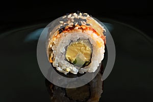 Sushi roll with salmon and sesame on a black background