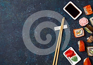 Sushi roll set with chopstick and soy sauce on blue background. Copy space, top view