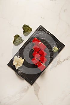 Sushi roll with tuna with red flying fish roe Tobiko on top. Hearts of dried herbs on marble background