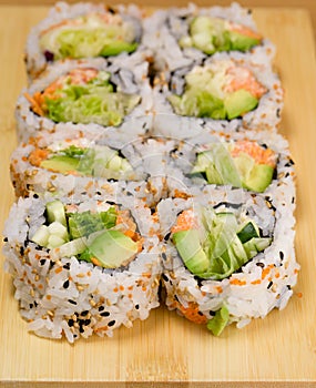 Sushi roll with zucchini, crab meat, salad, avocado and carrots, covered with caviar, black and white sesame