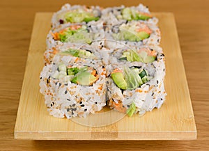 Sushi roll with zucchini, crab meat, salad, avocado and carrots, covered with caviar, black and white sesame