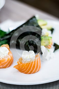 Sushi rolled with salmon fish and filadelfia cheese, temaki sushi in the background