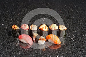 Sushi rolls on black marble background. Fresh Hosomak, Maki, Nigiri, Tempura, Uramaki, Philadelphia pieces with rice, nori, fish
