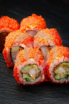 Sushi rolls california with snow crab, cream cheese, cucumber, sesame seeds and masago caviar on black background with