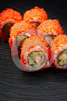 Sushi rolls california with snow crab, cream cheese, cucumber, sesame seeds and masago caviar on black background with