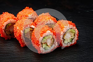 Sushi rolls california with snow crab, cream cheese, cucumber, sesame seeds and masago caviar on black background with