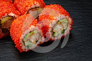 Sushi rolls california with snow crab, cream cheese, cucumber, sesame seeds and masago caviar on black background with