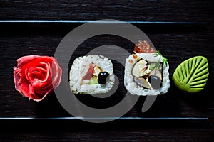 Sushi rolls with caviar, ginger, wassabi and chopsticks top view on black tableboard. Japanese food concept.