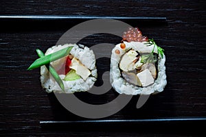 Sushi rolls with caviar, green onion, philadelphia, cucumber, omelette top view on black tableboard. Japanese food concept. Still