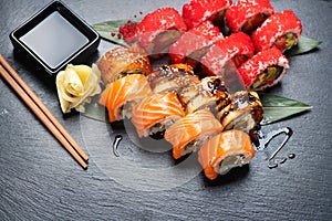 Sushi rolls closeup. Japanese food in restaurant. California sushi roll set with salmon, eel, vegetables and flying fish caviar