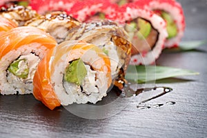 Sushi rolls closeup. Japanese food in restaurant. California sushi roll set with salmon, eel, vegetables and flying fish caviar