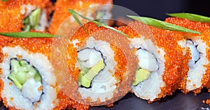 Sushi rolls closeup. Japanese food in restaurant. California sushi roll set with salmon, eel, vegetables and flying fish caviar.
