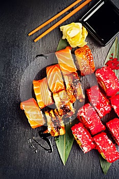 Sushi rolls closeup. Japanese food in restaurant. Roll with salmon, eel, vegetables and flying fish caviar on black slate