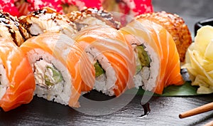 Sushi rolls closeup. Japanese food in restaurant. Roll with salmon, eel, vegetables and flying fish caviar on black slate