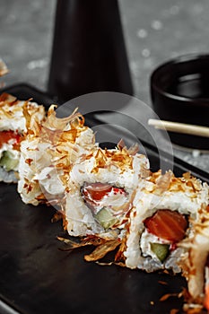 sushi rolls with cream cheese, fried salmon, tuna shavings or dried bonito, cucumber, nori. Chopsticks holding fresh