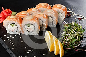 Sushi Rolls with cucumber, shrimp, salmon and Cream Cheese inside on black slate isolated. Philadelphia roll sushi with shrimp.