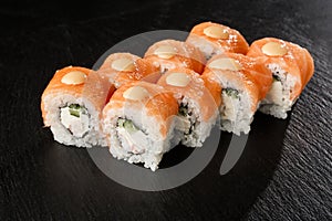 Sushi Rolls with cucumber, shrimp, salmon and Cream Cheese inside on black slate isolated. Philadelphia roll sushi with shrimp.